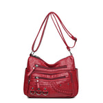 Red PU leather crossbody bag with front zip layers, braided pocket, and 3 ring details