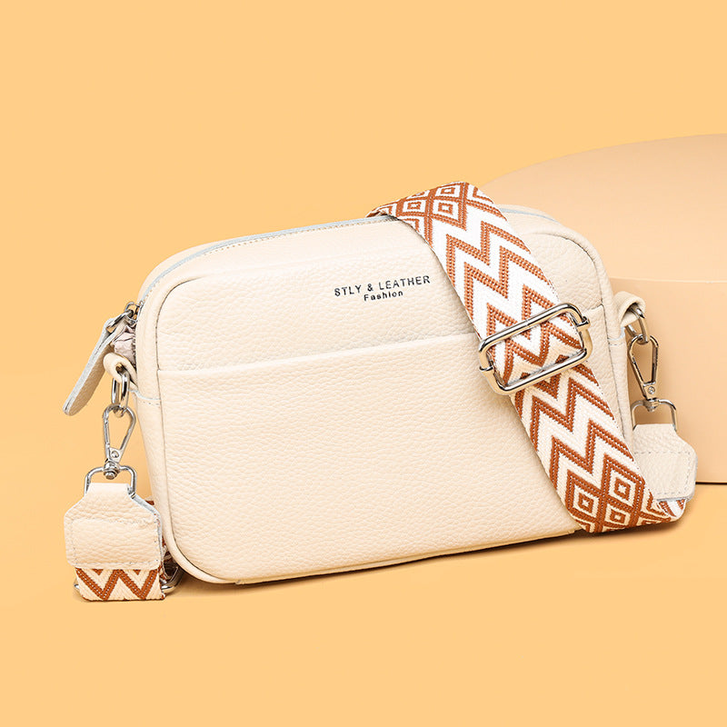 Genuine leather crossbody bag with cream body, patterned wide strap, and silver buckle hardware