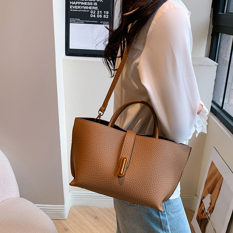 Brown textured PU bucket tote bag worn on shoulder with front zipper and gold trim.