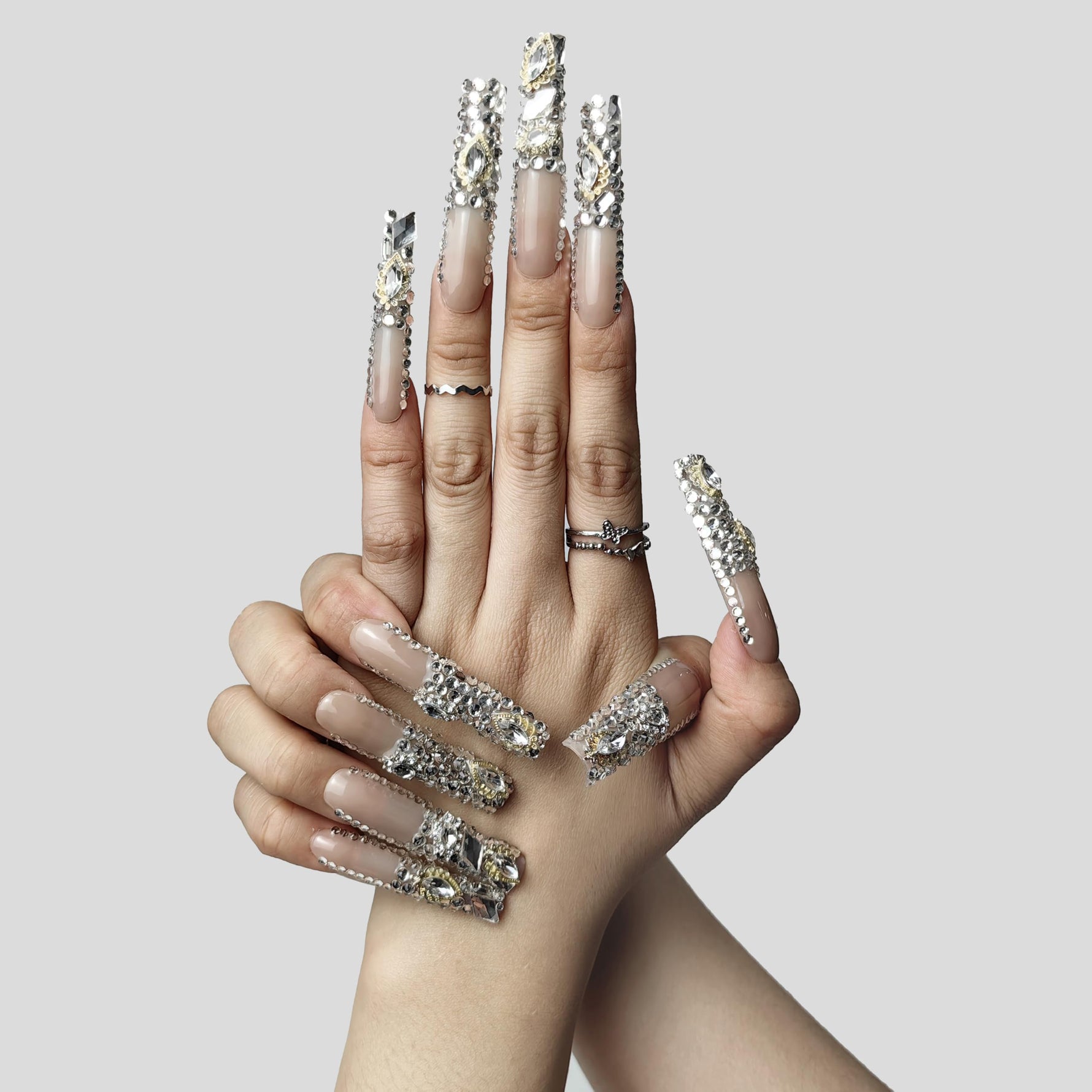 Blush short press-on nails with silver rhinestone borders and center stones, on hands