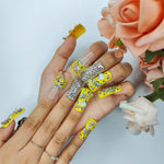 Duck-themed yellow rhinestone nails on hand, medium square with nude tips