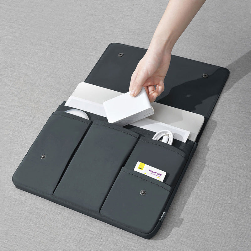 Black laptop bag sleeve open on surface, showing cable pocket and notebook slot