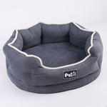 Grey round removable pet bed mattress with white piping and logo patch on front