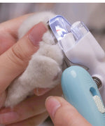 Light blue pet LED nail grinder with clear LED shield over a pet paw