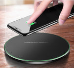 Black wireless charging pad with green LED ring, hand placing a smartphone on top