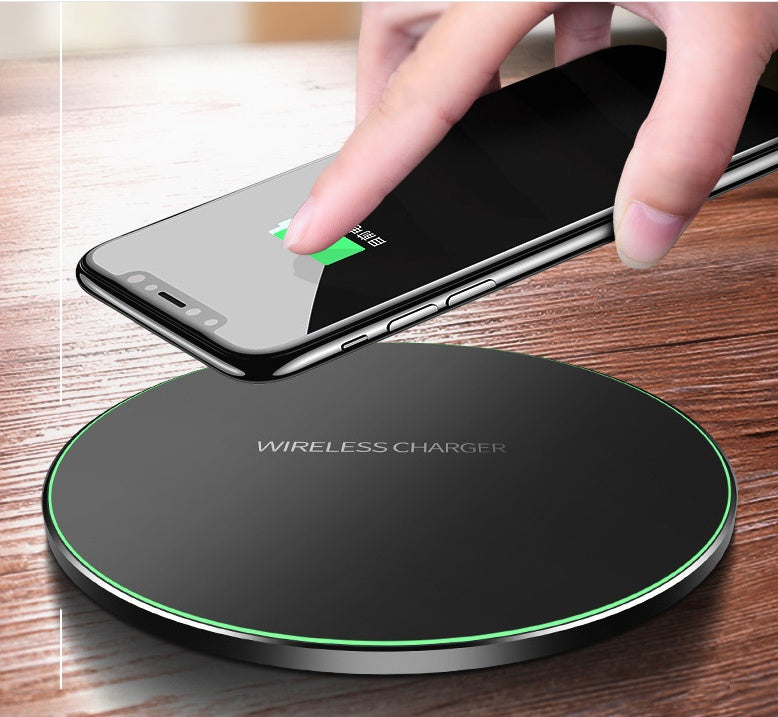 Black wireless charging pad with green LED ring, hand placing a smartphone on top