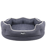 Blue round pet bed mattress with white piping and logo patch, front view