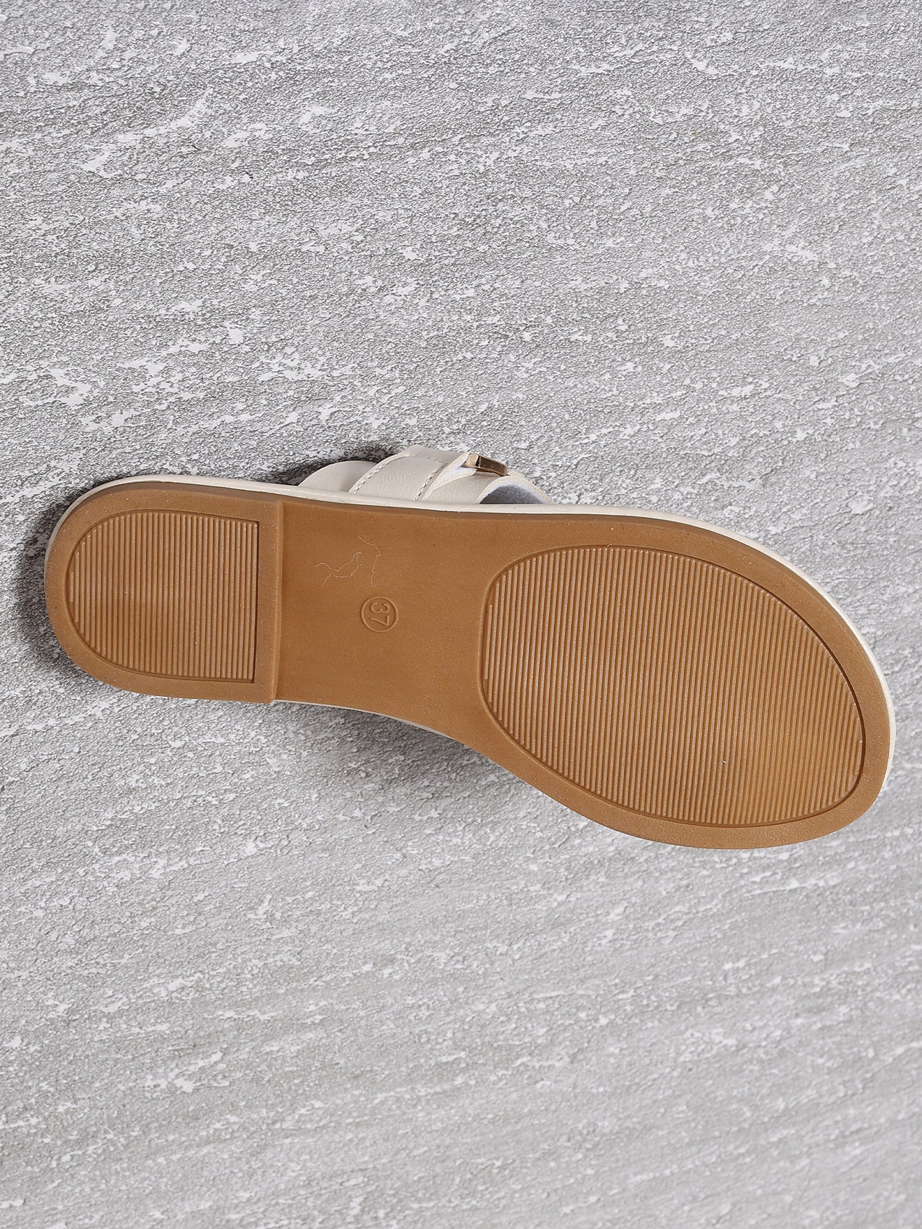 Women’s flat heel leisure slippers outsole in light tan with textured tread and logo mark
