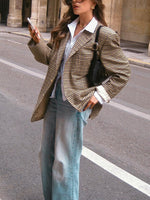 Plaid blazer with notch lapels and long sleeves, worn over a white button-up shirt