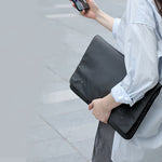 Black laptop bag sleeve held in hand, front flap with snap buttons and pockets