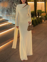 Ivory pleated maxi dress with long sleeves and draped cowl neckline, standing