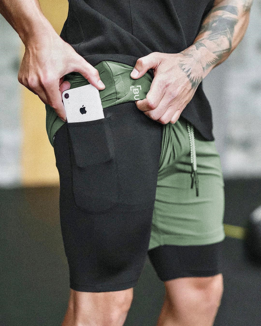 Men's black sports shorts with front pouch pocket, drawstring waist, and inner compression layer