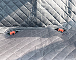 Quilted dog car seat cover with diamond stitching and small orange clip tabs on fabric