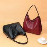 Red and black hobo bucket bags with zipper, shoulder straps and tassel pulls