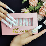 White press-on nails with bow and bead details, arranged on a display tray