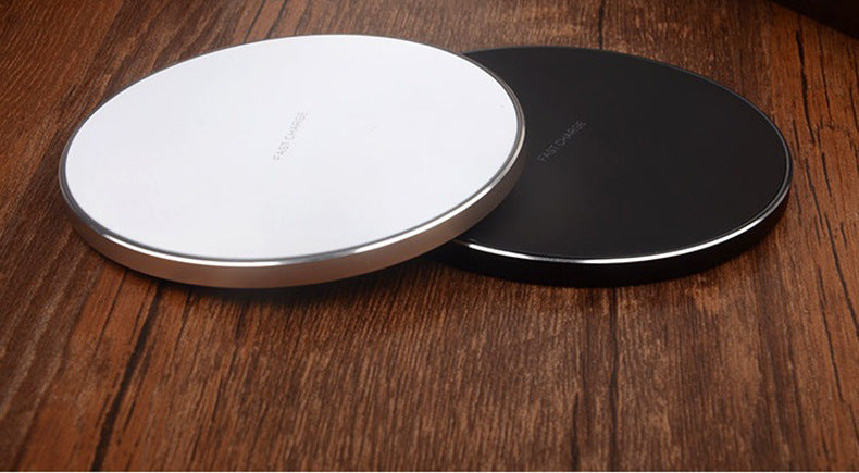 Round wireless charging pad pair, one white and one black, on a wood surface