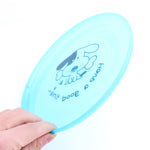 Silicone dog flying disc, light blue close-up held in hand with dog graphic