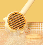 Yellow grooming brush with circular brown pin pad and wet bristles