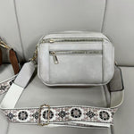Light gray crossbody bag with front zippers and floral embroidered strap, gold-tone hardware