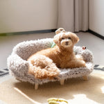 Luxury wooden pet bed with gray-and-white shag cover and small brown dog lying inside