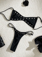 Two-piece bikini set with black triangle top and tie-side bottom with silver eyelet trim