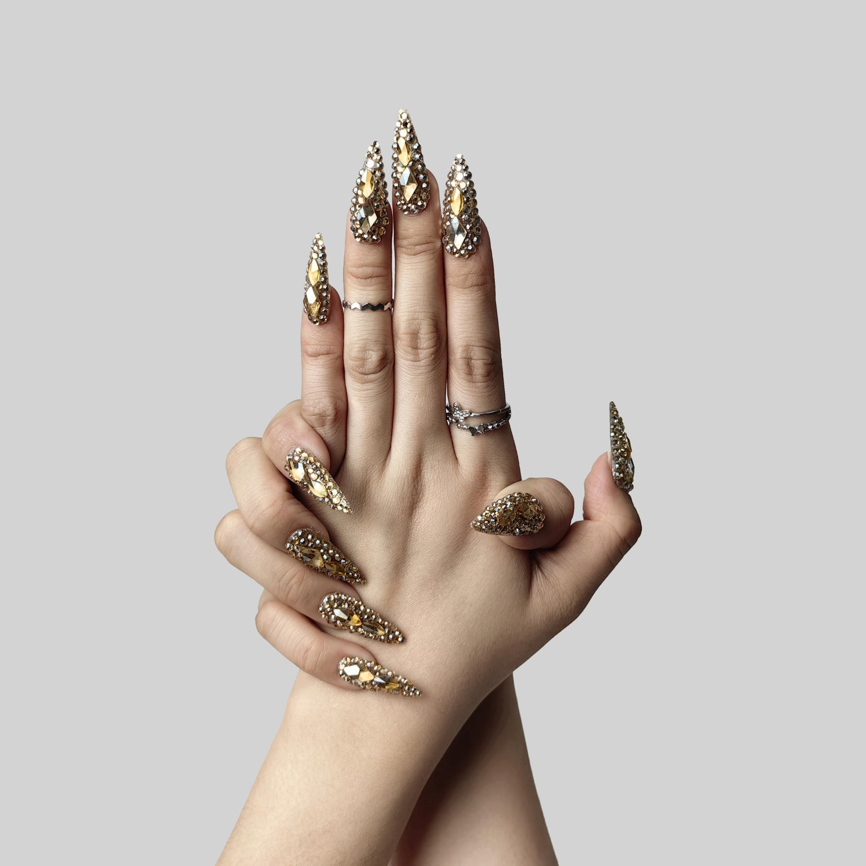 Almond press-on nails with gold and crystal rhinestone sparkle, shown on hands