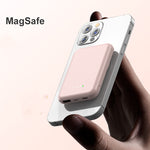 Pink magnetic wireless power bank resting behind a smartphone with charging indicator