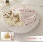 Round plush pet bed in pink plush, cat lying inside the opening