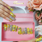 Duck-themed yellow rhinestone nails with clear accent tips, medium square