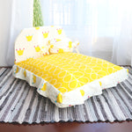 Small teddy pet bed with yellow patterned base and crown print headrest