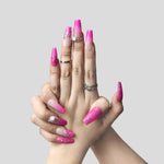 Short press-on acrylic nails in bright pink with glitter specks and rhinestone details