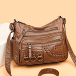 Brown PU leather crossbody bag with top zipper, front pockets, braided detail, and 3 rings
