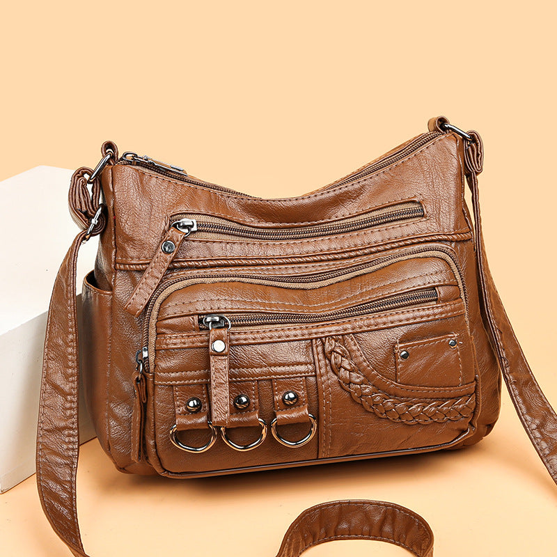 Brown PU leather crossbody bag with top zipper, front pockets, braided detail, and 3 rings