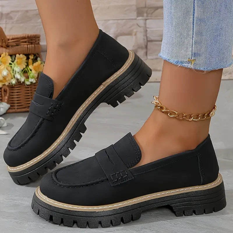 Women’s matte black flat loafer shoes with round toe, buckle strap, and thick tread sole