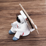 Astronaut resin phone stand close side view with white spaceman holding a smartphone