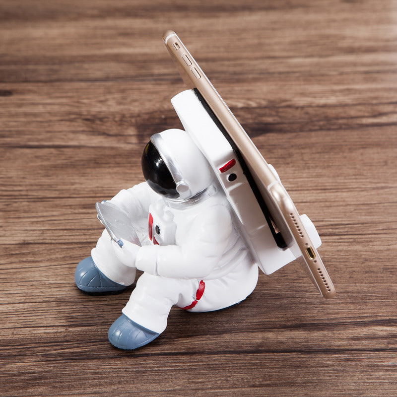 Astronaut resin phone stand close side view with white spaceman holding a smartphone