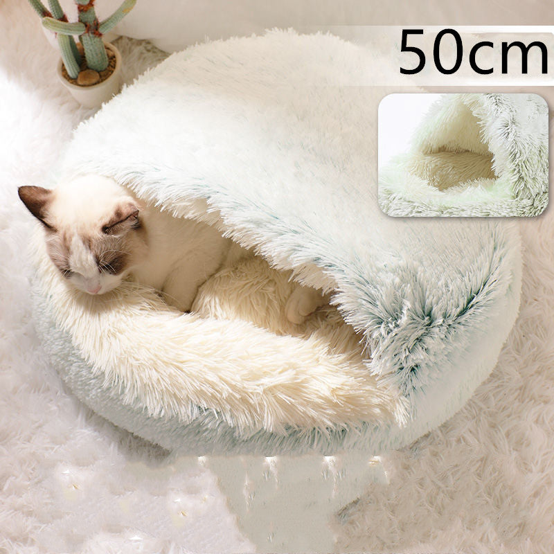 Cream round plush pet bed with teal shag trim, cat lying inside.