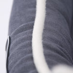Grey pet bed mattress fabric with white seam strap and stitched texture, close-up