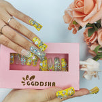 Duck-themed yellow rhinestone nails on hand, medium square, with open box