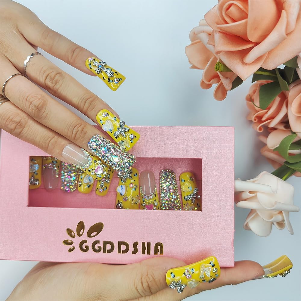 Duck-themed yellow rhinestone nails on hand, medium square, with open box