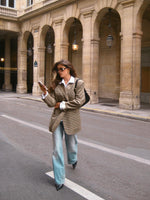 Plaid blazer with notch lapels and long sleeves, worn with light blue jeans and a white shirt