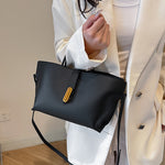 Black textured PU bucket tote bag with front zipper, short handles, and long strap.