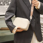Genuine leather crossbody bag on person with cream body and patterned wide shoulder strap