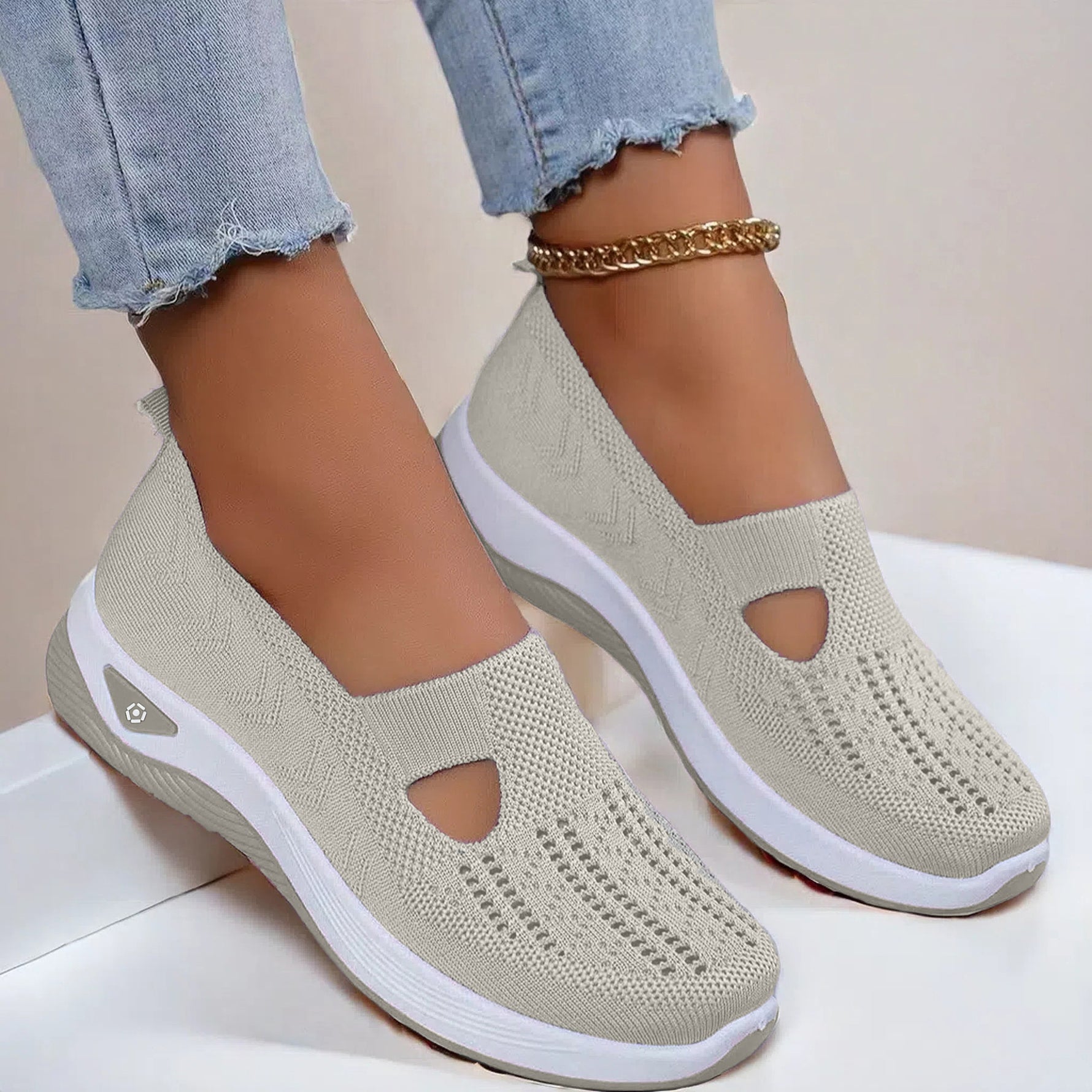 Beige mesh slip-on flat shoes with oval cutouts and white cushioned soles