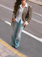 Plaid blazer with notch lapels and long sleeves, worn open over a white shirt and jeans