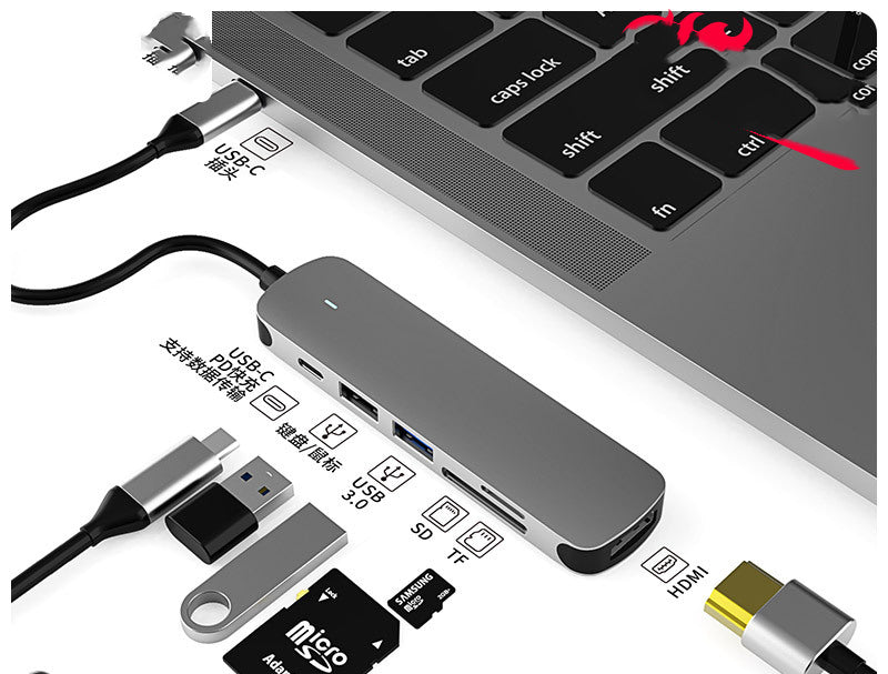 USB-C hub docking station connected to laptop, visible USB ports, HDMI output and SD slot