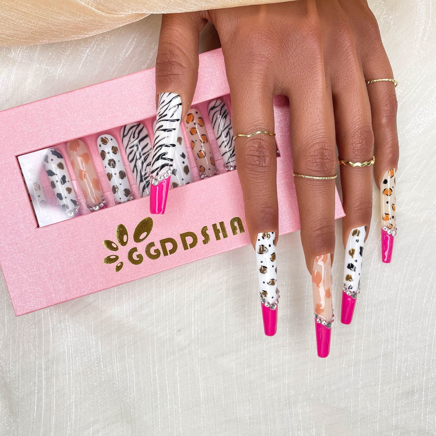 Long stiletto press-on nails on hands with zebra, leopard, and fuchsia accents