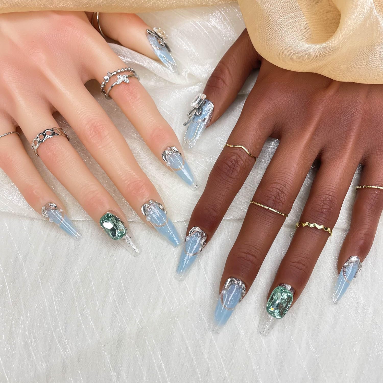 Press-on nails with blue streak design, silver charms, and oval green rhinestone