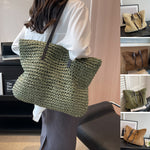 Woven shoulder beach bag in dark green with black top handles and strap