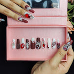 Long press-on nails set in open box, deep red and white with large red jewel accents